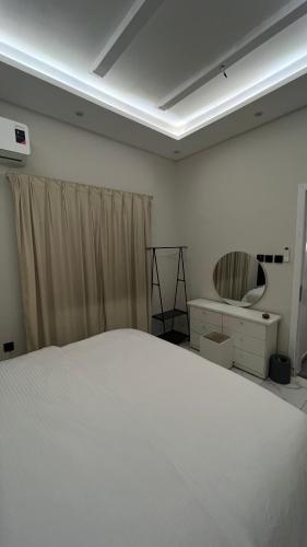 a bedroom with a white bed and a mirror at Your first comfortable residence in Riyadh