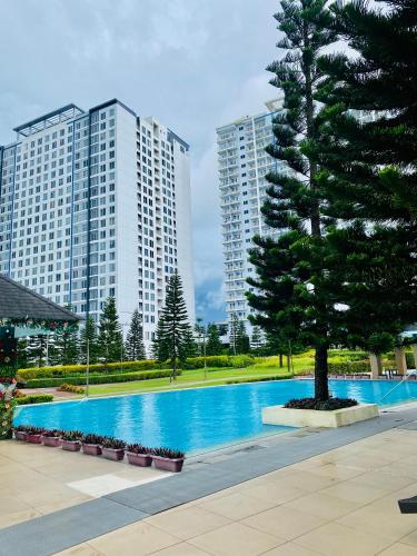a swimming pool with a tree and two tall buildings at Casa Arabella - Wind Residences Tower 5 2018 in Tagaytay