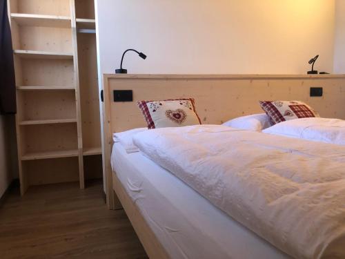 a bedroom with a bed with a headboard and shelves at B&B Tilde in Tesero