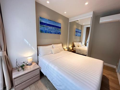 a bedroom with a large white bed and a mirror at Diamond Phuket Bang Tao in Bang Tao Beach