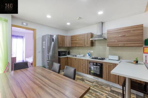 a kitchen with a wooden table and a refrigerator at A lovely 4BR home with private POOL & BBQ by 360 Estates in Is-Swieqi