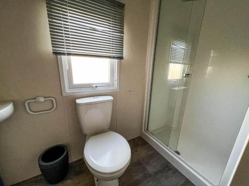 a bathroom with a toilet and a glass shower at Superb 8 Berth Caravan For Hire At St Osyth Beach In Essex Ref 28055cw in Clacton-on-Sea