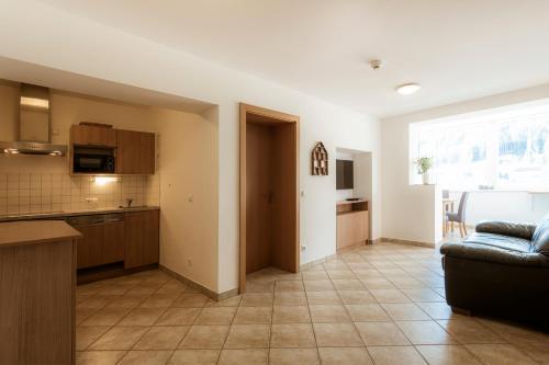 a kitchen and a living room with a couch at Panorama Spa Lodges DAS.SCHILLER in Bad Gastein