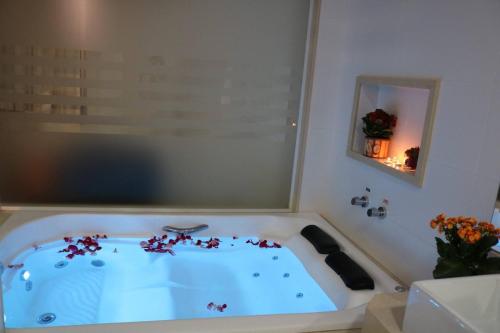 Laguna Plaza Hotel في برازيليا: حوض استحمام مع الزهور في الحمام