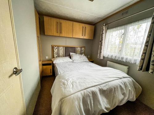 a small bedroom with a bed and a window at Superb 6 Berth Caravan With Decking At Seawick Holiday Park, Essex Ref 27009mv in Clacton-on-Sea