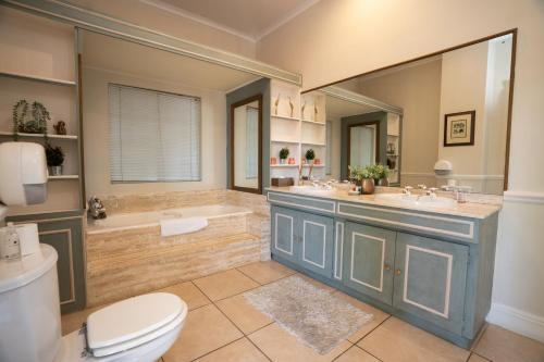 ヨハネスブルグにあるLittle Tuscany Boutique Hotelのバスルーム(洗面台2台、バスタブ、トイレ付)