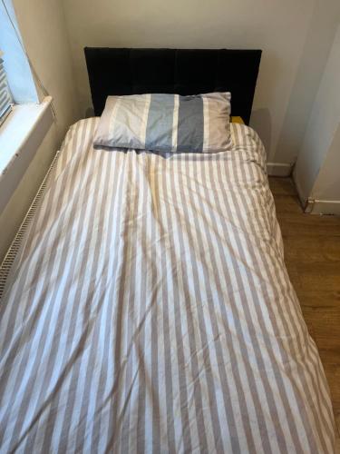 a bed with a striped bedsheet in a bedroom at 10 Cornwell Avenue in Kent