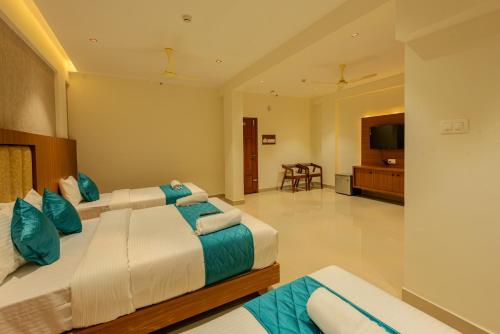 a hotel room with two beds and a television at Hotel Stay Bella Kozhikode in Kozhikode