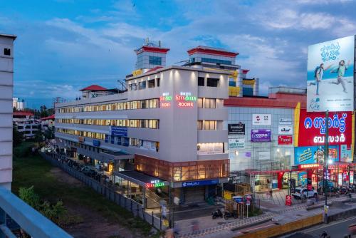 a tall white building with many signs in a city at Hotel Stay Bella Kozhikode in Kozhikode