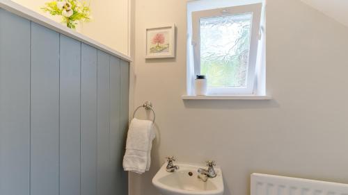 uma casa de banho branca com um lavatório e uma janela em The Eyrie em Ashbourne