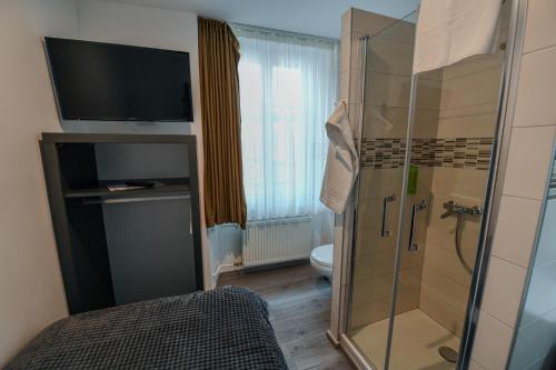 a bathroom with a shower and a toilet and a television at Hotel de France in La Chaux-de-Fonds