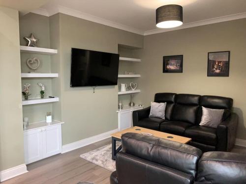 a living room with a leather couch and a flat screen tv at Church View in York
