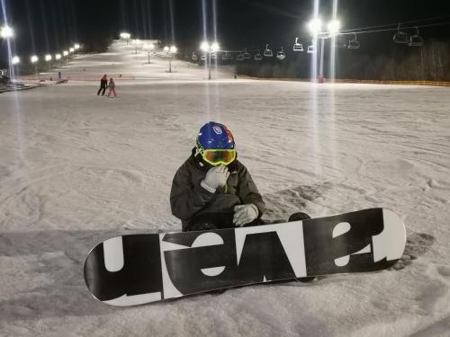a person sitting in the snow with a snowboard at Chata w Bieszczadzie apartamenty i domki z basenem Bieszczady in Polańczyk