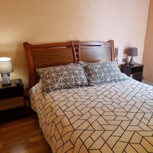 Hotel Arauco Ovalle في اوفايي: سرير في غرفة نوم مع مصباحين وطاولتين