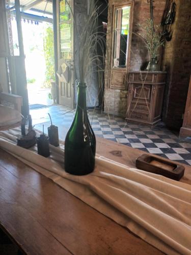 Hostería Casa de Campo في شاسكوموس: وجود زجاجة خضراء موضوعة فوق طاولة خشبية