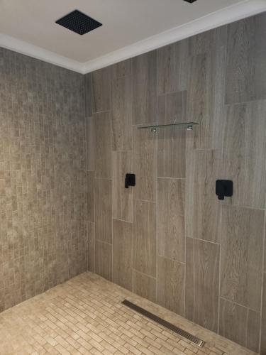 a bathroom with a shower with wooden tiles at Tsitsikamma Garden Chalets in Stormsrivier