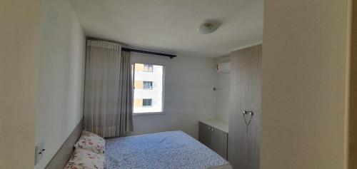 ein kleines Schlafzimmer mit einem Bett und einem Fenster in der Unterkunft Meu Apê in Aracaju