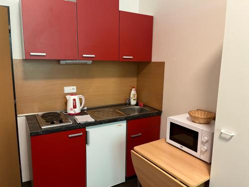 een kleine keuken met rode kasten en een magnetron bij Apartmán NOVOHRADKY 22 in Benešov nad Černou