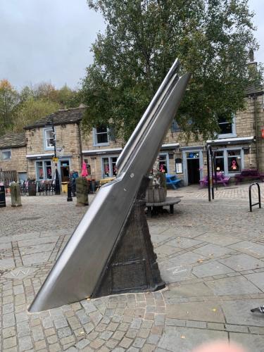 a metal slide in a park with a building at Stylish apartment in the centre of Hebden Bridge. in Hebden Bridge