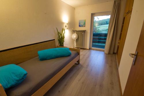 a bedroom with a bed with blue pillows and a window at Nature Paradies am Seeberg in Heidenheim an der Brenz