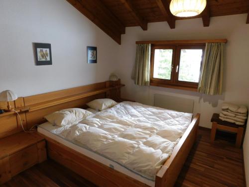 una camera da letto con un letto con lenzuola bianche e una finestra di Ferienwohnung Silberdistel 2. Obergeschoss a Bellwald