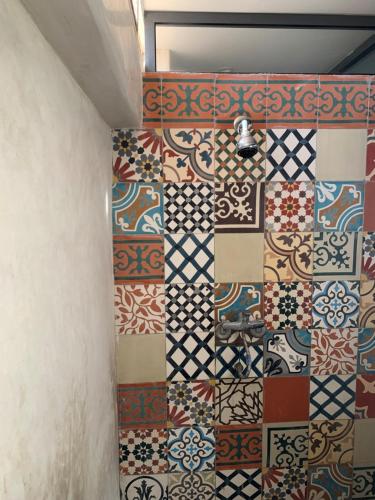 een badkamer met verschillende tegels op de muur bij Hostel The Endless House Anchor point in Taghazout