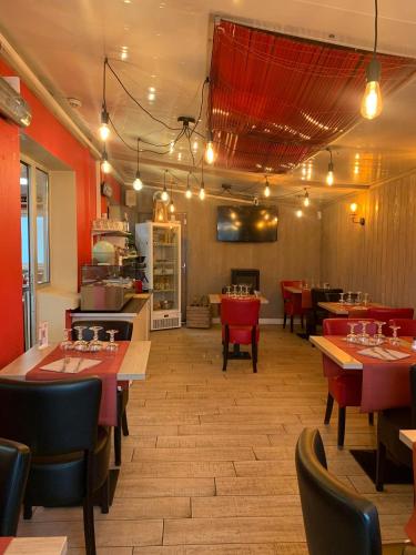 a restaurant with tables and chairs and a kitchen at Au Petit Bonheur in La Tranche-sur-Mer