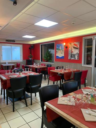 a restaurant with tables and chairs and red walls at Au Petit Bonheur in La Tranche-sur-Mer