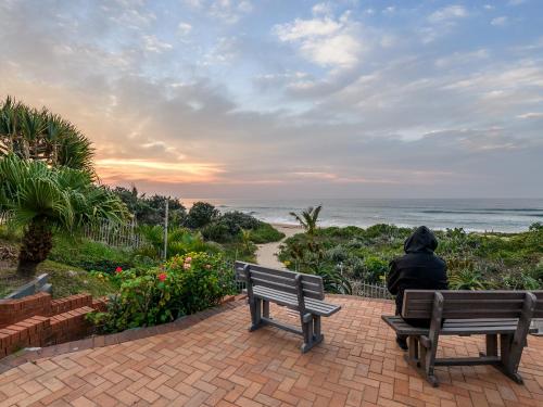 a person sitting on a bench looking at the ocean at Margate Beach Club in Margate