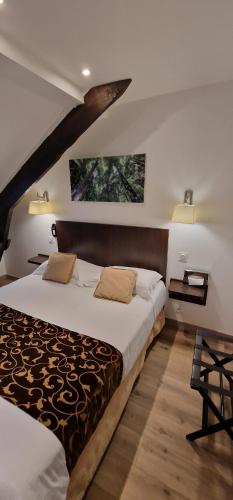 a bedroom with a bed and two pictures on the wall at Hotel le Bellevue in Guer