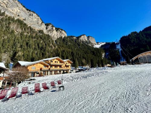 a group of chairs in the snow in front of a lodge at Hameau des Prodains - Hôtel in Morzine