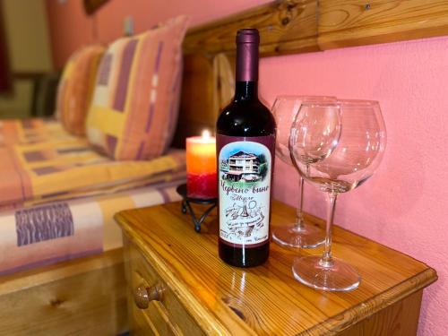 a bottle of wine sitting next to two wine glasses at Family Hotel Savov in Chepelare