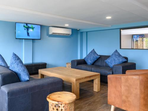 a living room with blue walls and couches and a table at Margate Beach Club in Margate