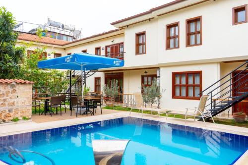a pool in front of a house with a blue umbrella at Kaleici Aparts Antalya in Antalya