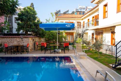 a swimming pool with a table and an umbrella at Kaleici Aparts Antalya in Antalya