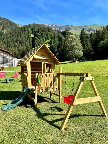 a wooden playground with a slide and a play structure at Hameau des Prodains - Hôtel in Morzine