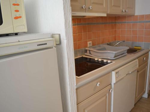 une petite cuisine avec un évier et une cuisinière dans l'établissement Studio lumineux à 30m de la plage, balcon, clim, commerces à côté - FR-1-226-444, à Sainte-Maxime