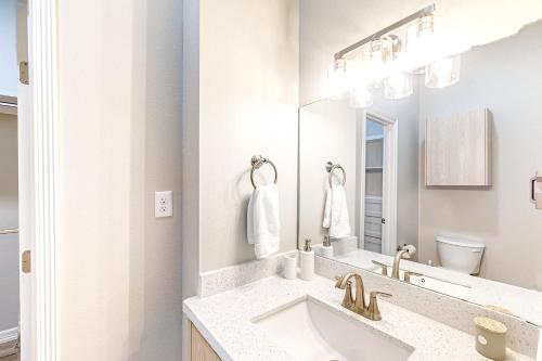 a white bathroom with a sink and a mirror at Uvalde Avenue Abode in McAllen