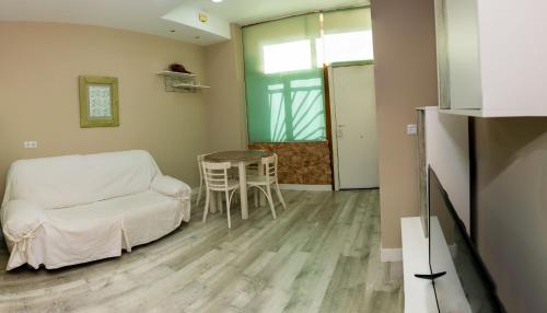 Estudio en el pleno centro de Alicante by Renthas في أليكانتي: غرفة معيشة مع طاولة وأريكة بيضاء