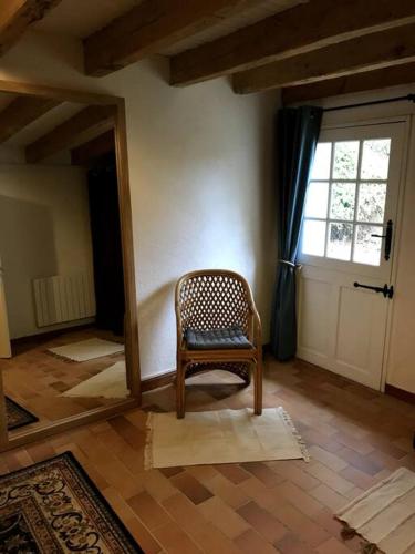 a chair sitting in a room with a mirror at Longère de charme in Saint-Cyran-du-Jambot