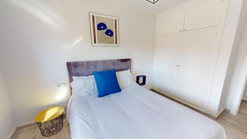um quarto com uma grande cama branca com almofadas azuis em Casa Claveles - A Murcia Holiday Rentals Property em Santiago de la Ribera