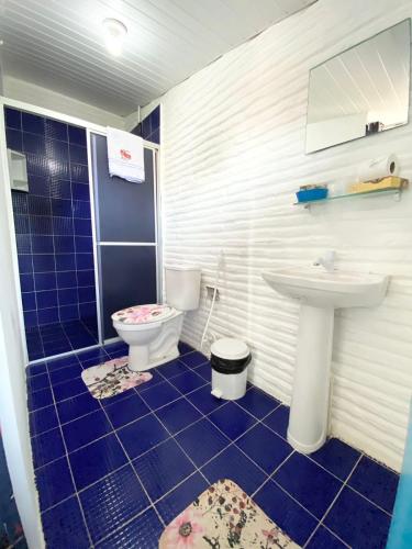 a blue tiled bathroom with a toilet and a sink at Pousada & Food 3 Abelhas in Cumbuco