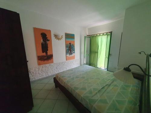 a bedroom with a bed and paintings on the wall at CosmoCom Moradias Residence Capo Verde in Santa Maria