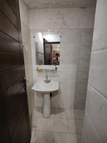 Ein Mann fotografiert ein Badezimmer mit Waschbecken. in der Unterkunft 2 Bedrooms Standard Apartment Islamabad-HS Apartments in Islamabad