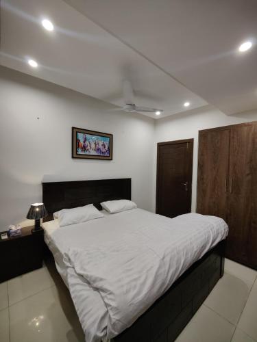 ein Schlafzimmer mit einem großen Bett mit weißer Bettwäsche in der Unterkunft 2 Bedrooms Standard Apartment Islamabad-HS Apartments in Islamabad