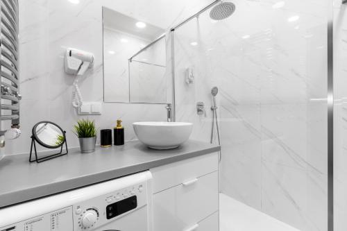 a white bathroom with a sink and a shower at Golden Apartments Warsaw - Luxury And Bright Apartment - Siedmiogrodzka 3 in Warsaw