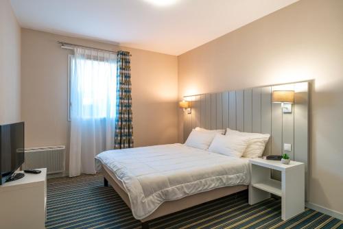 une chambre d'hôtel avec un lit et une télévision dans l'établissement Les Thermes 500 - Appt avec piscine partagée, à Concarneau