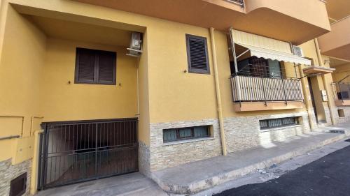 a yellow building with a gate and a balcony at Vespucci Holiday in Casteldaccia
