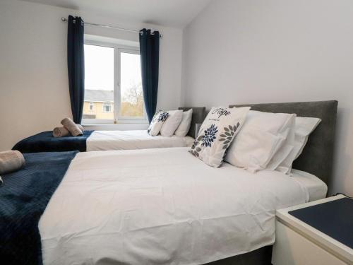 two beds in a room with a couch and a window at 3 Thrimby Court in Morecambe