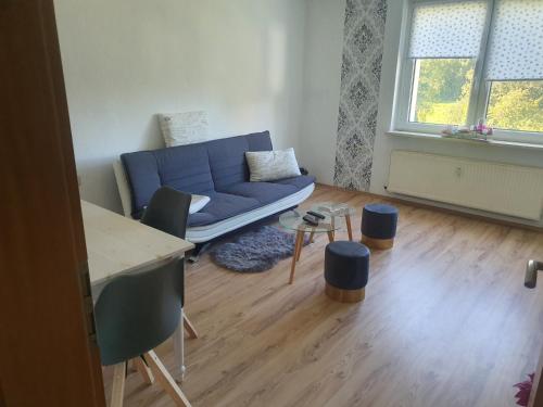 a living room with a blue couch and a table at Monteurwohnung Kuhfelde in Kuhfelde